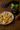 A jar of artisan Native Bush Honey with a glossy black label, gold detail, and green ribbon, beside shortbread cookies drizzled with honey on a rustic wooden table.