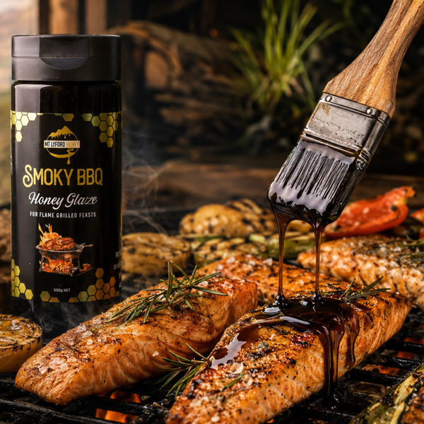 Smoky BBQ Honey Glaze being applied to grilled salmon with a brush, against a dark background.