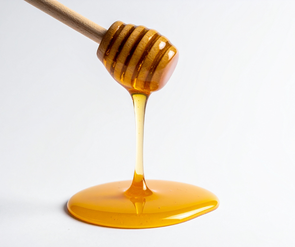 Wooden honey dipper shown drizzling honey